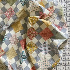 an old quilt is laying on top of a tablecloth with many different colors and patterns