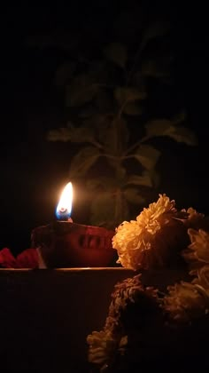 a lit candle sitting on top of a table next to flowers