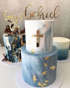 two cakes decorated with blue and gold designs on top of each other, one has a crucifix in the middle