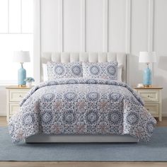 a bed with blue and white bedspread on top of it in a room