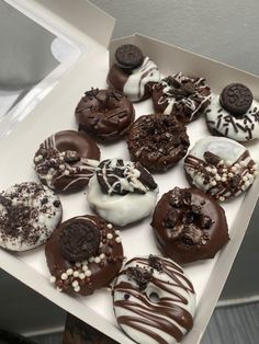 a box filled with lots of different flavored donuts on top of a table