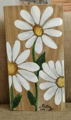 a painting of three white daisies on a brown background