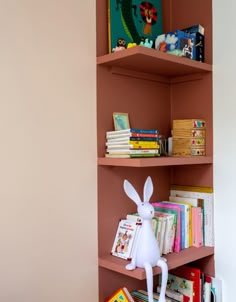 the bookshelf is filled with children's books and toys, including a toy rabbit