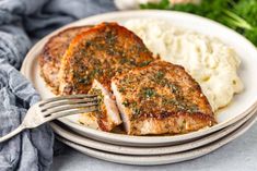 two pieces of pork chops on a plate with mashed potatoes