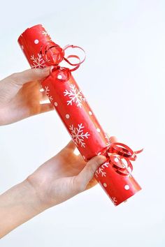 two hands holding red wrapped presents with snowflakes on them