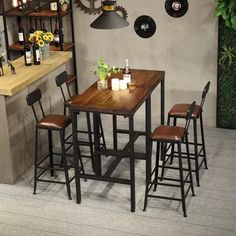 a small table with four stools in front of it and bottles on the wall