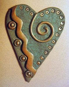 a heart shaped brooch sitting on top of a white table next to a wall