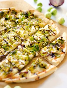 a pizza sitting on top of a cutting board covered in cheese and veggies