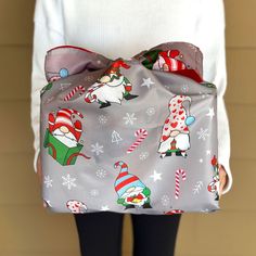 a woman is holding a bag with christmas decorations on it