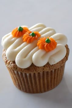 a cupcake with white frosting and orange decorations