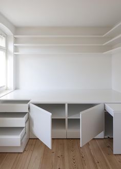 an empty room with white furniture and wooden floors