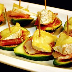 small appetizers are arranged on a white plate with toothpicks in them