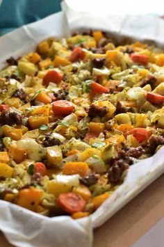 a casserole dish with sausage, potatoes and carrots in it on a table