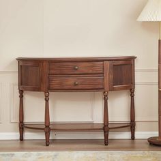 a wooden table sitting next to a lamp on top of a hard wood floor