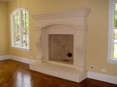 an empty living room with a fireplace in the center and two windows on either side