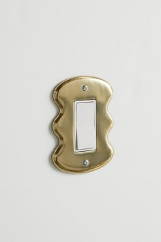 a single light switch cover in gold on a white wall