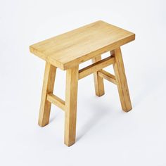 a small wooden stool sitting on top of a white floor