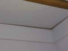 the corner of a white room with a wooden beam