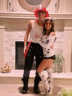 a man and woman dressed up in costumes standing next to each other near a fireplace