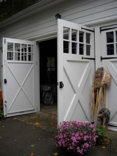 an open white barn door with flowers in the foreground