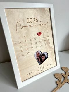 a wooden calendar with two hearts on it and a couple's date in the middle