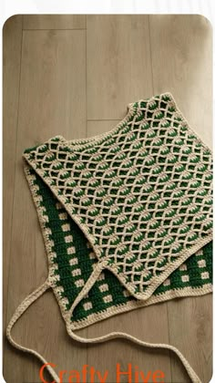 a green and white crocheted blanket laying on the floor