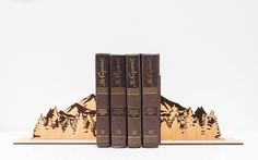 three bookends made out of wood with mountains and trees on the top one