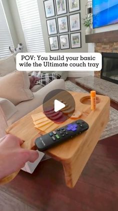 a person holding a remote control in front of a table with cheese and crackers on it