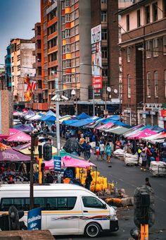 a busy city street filled with lots of people and colorful umbrellas on top of buildings