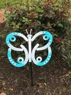 a blue and white butterfly sitting on top of a planter in front of some bushes