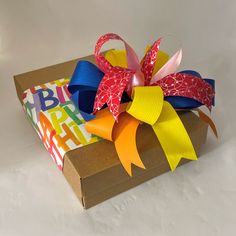 a gift wrapped in colorful paper and tied to a brown cardboard box with the words happy birthday on it