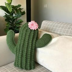 a crocheted cactus sitting on top of a couch next to a potted plant