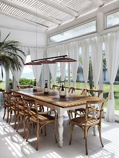 a dining room table with chairs and an umbrella over it in front of large windows