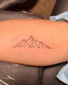 a small mountain tattoo on the arm