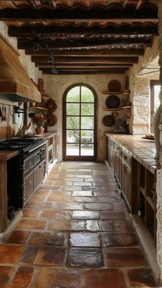 a kitchen with stone flooring and an arched doorway leading into the dining room area