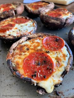 baked pizzas with pepperoni and cheese are on a baking sheet, ready to be eaten