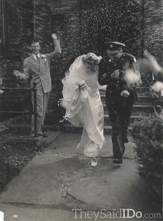 an old black and white photo of a bride and groom walking down the street with confetti thrown over them