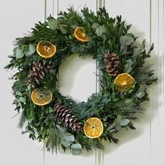 a wreath with oranges, pine cones and evergreen leaves