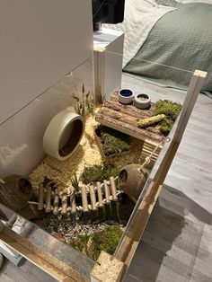 a table that has some plants and rocks in it on top of the floor next to a bed