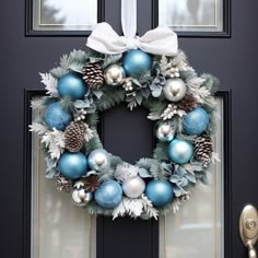 a wreath with blue and silver ornaments hanging on the front door to give it a festive feel