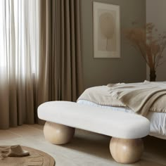 a white bed sitting next to a window in a room with curtains on the windowsill