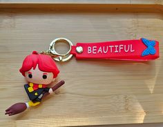 a plastic keychain with a cartoon character holding a broom and the word beautiful on it