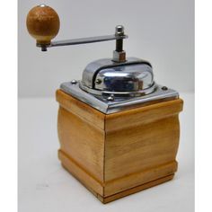 an old fashioned grinder with a wooden handle on it's head and wood grain in the bottom