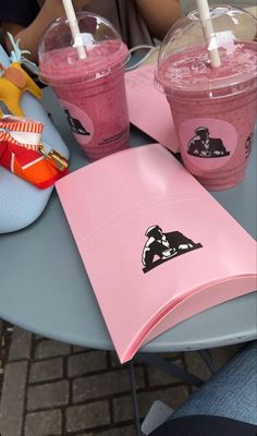 two pink drinks sitting on top of a table