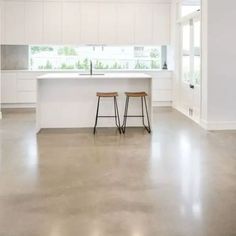 two stools are sitting in front of the kitchen counter and island with an open window