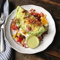 a white plate topped with lettuce and tomatoes next to a knife and fork