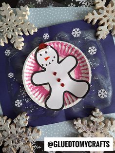 a paper plate with a snowman on it next to some fake snowflakes