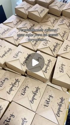 many brown boxes with writing on them are stacked up and ready to be used as place cards