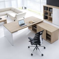 an office desk with a laptop computer on top of it next to a couch and bookcase