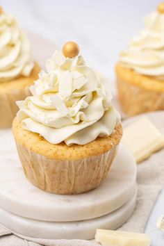 two cupcakes with white frosting sitting on a plate next to some butter